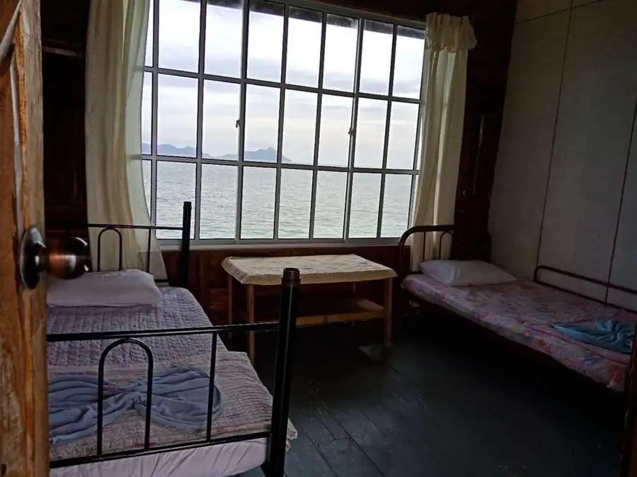 Simple and comfortable double room interior at Grand Dive Resort featuring two single beds and a large window with ocean views.